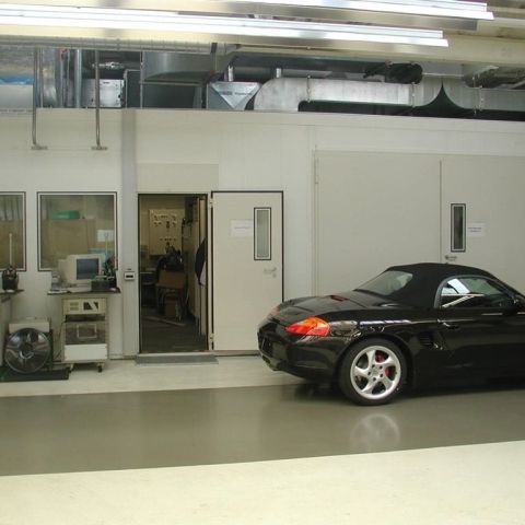 Schwarzer Porsche steht vor einer weißen Schallschutzkabine für die Industrie