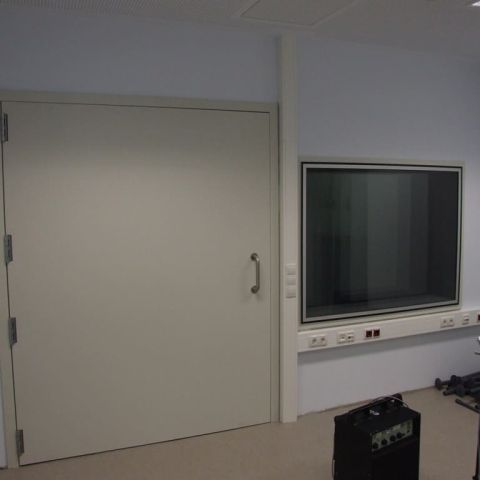 Helle Wand mit Lärmschutztür links und Schallschutzfenster rechts